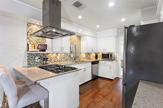kitchen with appliances with stainless steel finishes, island range hood, a peninsula, a textured wall, and a sink