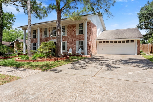 neoclassical / greek revival house with driveway, brick siding, and an attached garage