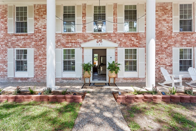 view of exterior entry featuring covered porch and brick siding