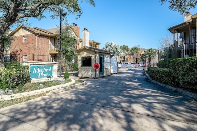 view of street with curbs, a residential view, traffic signs, a gated entry, and a gate