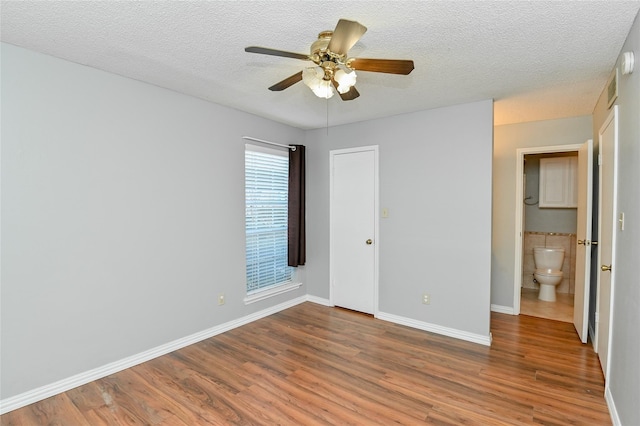 unfurnished bedroom with baseboards, a ceiling fan, a textured ceiling, and wood finished floors