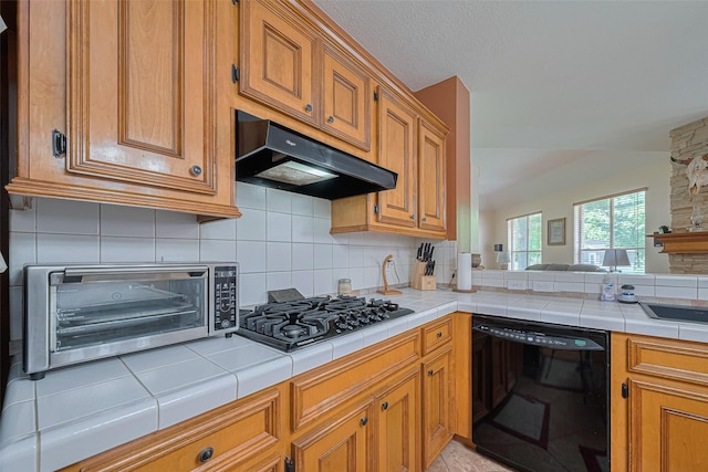 kitchen featuring black appliances, under cabinet range hood, tasteful backsplash, and brown cabinets