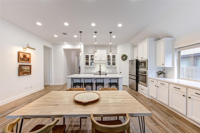 20447 Avelignese Way, Tomball, TX 77377 - kitchen featuring white cabinets, a center island with sink, light countertops, tasteful backsplash, and appliances with stainless steel finishes