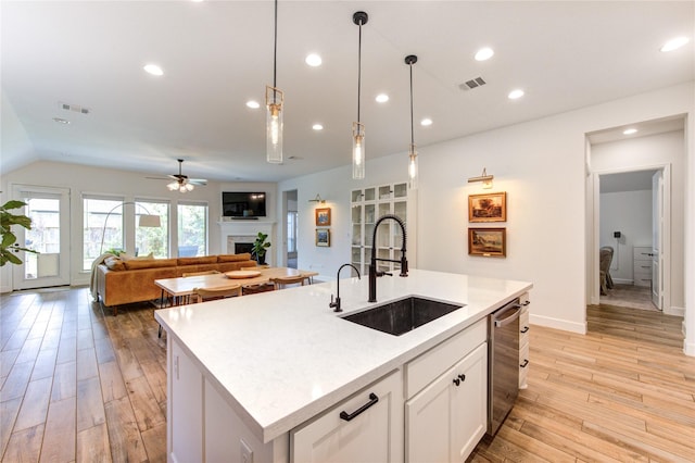 20447 Avelignese Way, Tomball, TX 77377 - kitchen with stainless steel dishwasher, visible vents, a sink, a fireplace, and light wood-type flooring