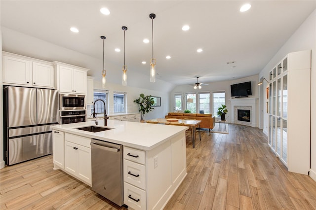20447 Avelignese Way, Tomball, TX 77377 - kitchen with a glass covered fireplace, ceiling fan, a sink, a center island with sink, and stainless steel appliances
