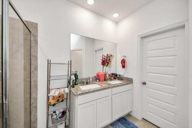 full bath featuring a sink, double vanity, a shower stall, and tile patterned flooring
