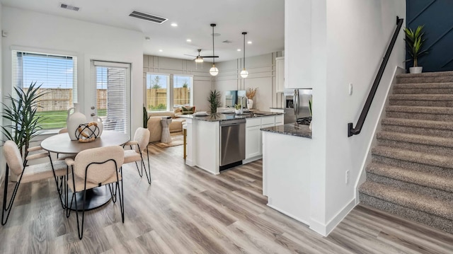 kitchen featuring stainless steel appliances, dark stone counters, visible vents, light wood finished floors, and white cabinets