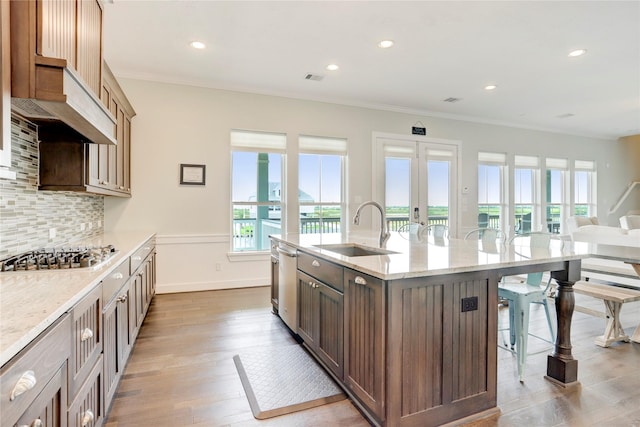 kitchen with a sink, a kitchen breakfast bar, wood finished floors, tasteful backsplash, and appliances with stainless steel finishes