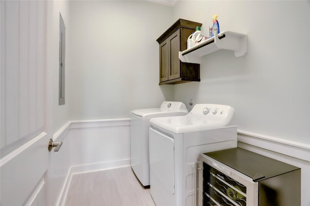 washroom featuring washing machine and clothes dryer, wainscoting, electric panel, and cabinet space