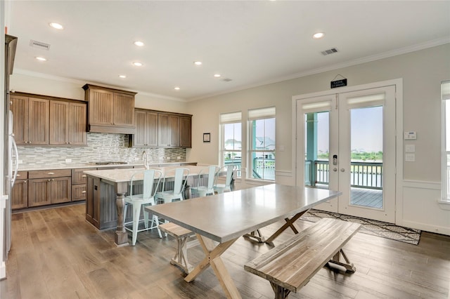 dining space with light wood-type flooring, visible vents, french doors, and ornamental molding