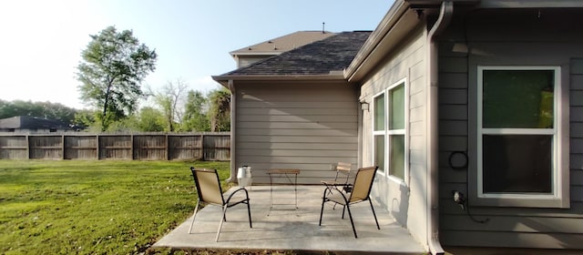 exterior space featuring a lawn, a patio, roof with shingles, and fence