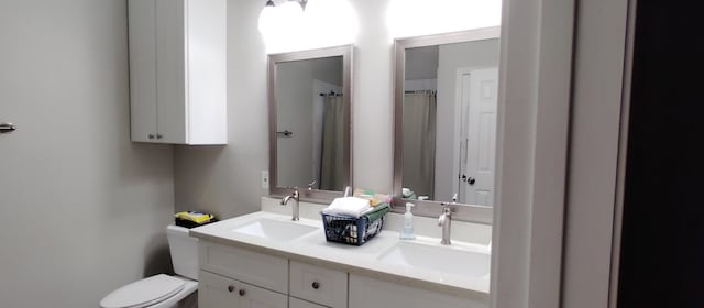 full bathroom with double vanity, toilet, and a sink