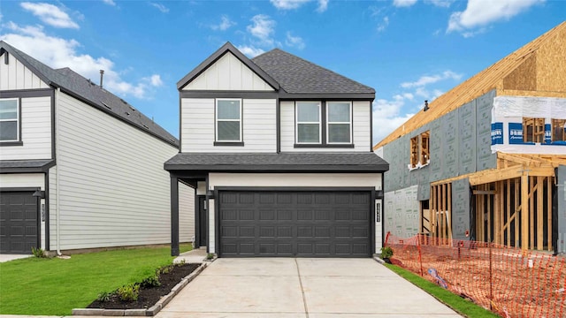 traditional home with an attached garage, concrete driveway, a shingled roof, and board and batten siding