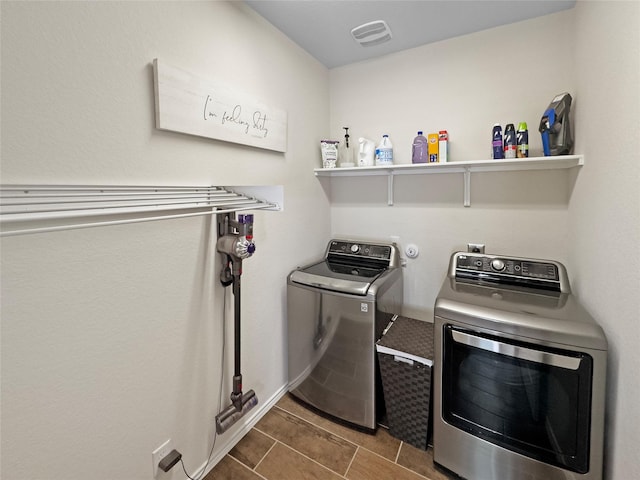 clothes washing area featuring washing machine and dryer, laundry area, visible vents, and dark tile patterned floors