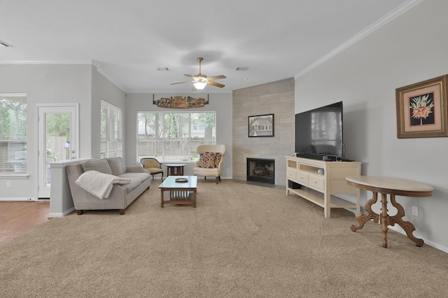 living area with carpet flooring, ornamental molding, baseboards, ceiling fan, and a tile fireplace