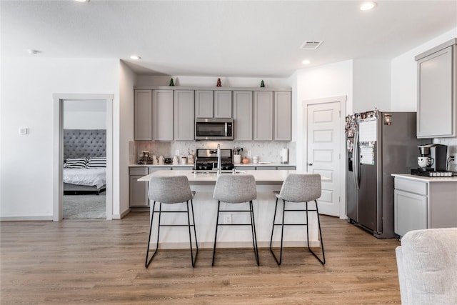13938 Red River Dr, Baytown, TX 77523 - kitchen with a breakfast bar area, stainless steel appliances, light countertops, and gray cabinets