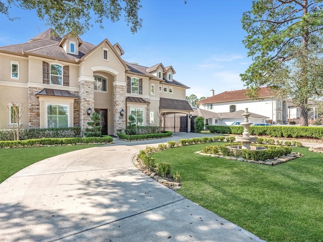 french country home featuring stone siding, stucco siding, curved driveway, and a front lawn