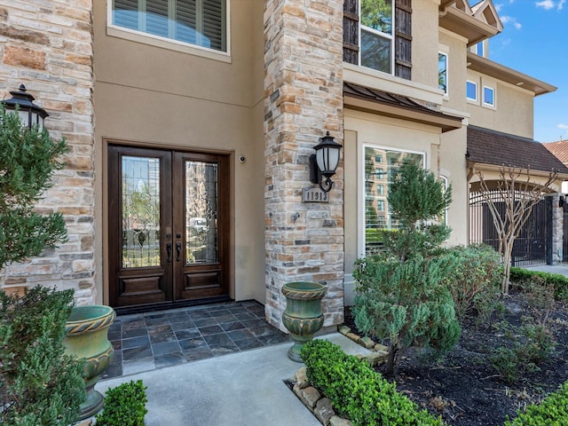 entrance to property with stucco siding, french doors, and stone siding