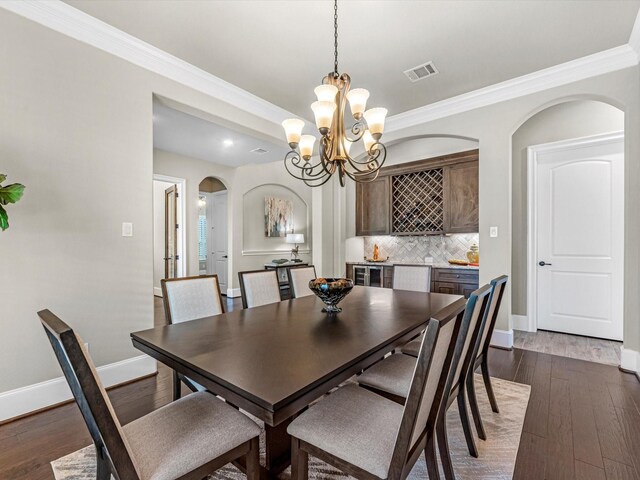 dining space with visible vents, dark wood finished floors, an inviting chandelier, arched walkways, and baseboards