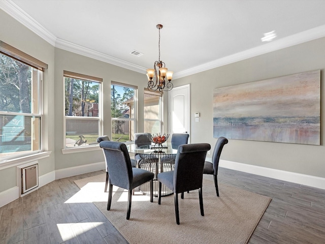 dining space with wood finished floors, visible vents, crown molding, an inviting chandelier, and baseboards