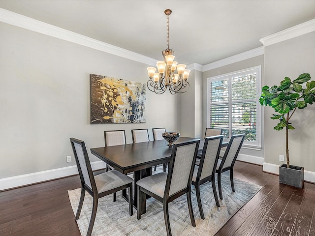dining space featuring crown molding, a notable chandelier, baseboards, and wood finished floors