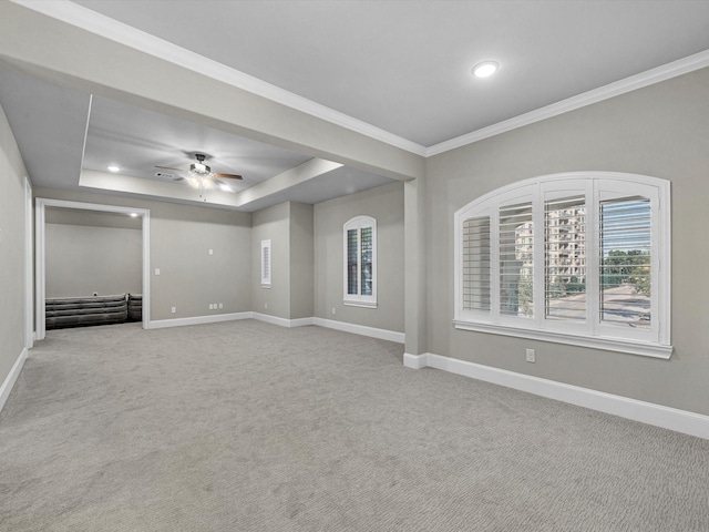 unfurnished living room featuring ceiling fan, crown molding, carpet flooring, a tray ceiling, and baseboards