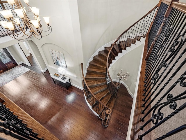 entrance foyer with baseboards, an inviting chandelier, stairs, hardwood / wood-style flooring, and arched walkways