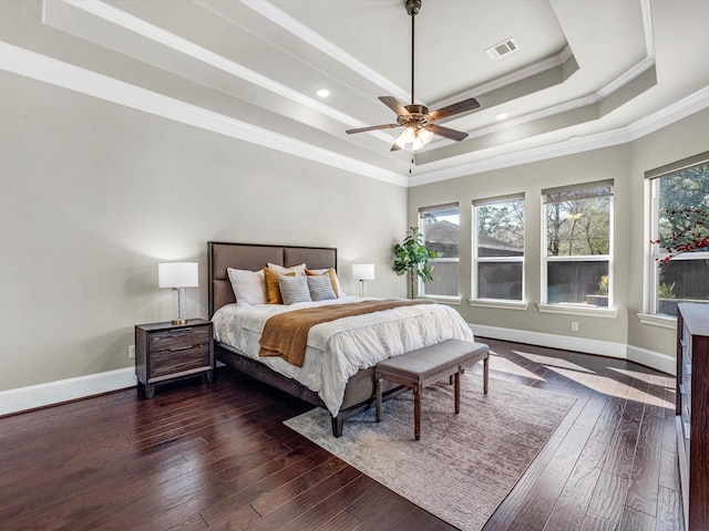 bedroom with hardwood / wood-style floors, visible vents, crown molding, a raised ceiling, and baseboards