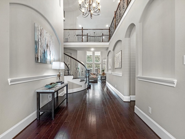 entrance foyer featuring baseboards, an inviting chandelier, stairs, hardwood / wood-style flooring, and a high ceiling