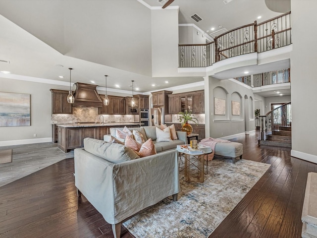 living area featuring stairway, dark wood-style flooring, ornamental molding, and baseboards