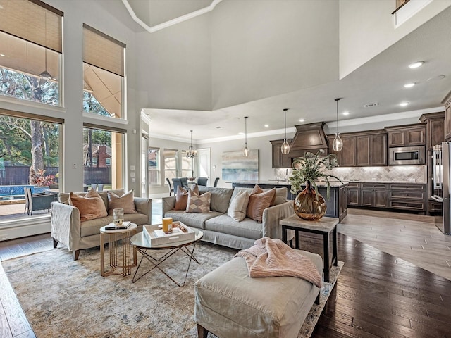 living area featuring hardwood / wood-style floors, plenty of natural light, crown molding, and a high ceiling