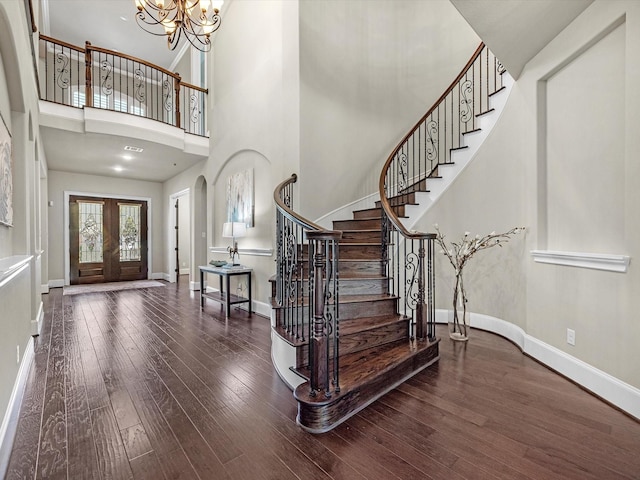 foyer with a high ceiling, stairway, baseboards, arched walkways, and hardwood / wood-style flooring