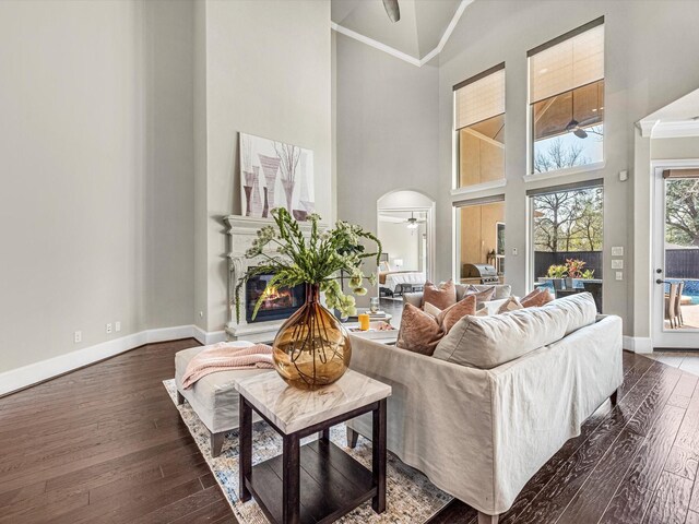 living room featuring baseboards, dark wood finished floors, ceiling fan, and a high ceiling