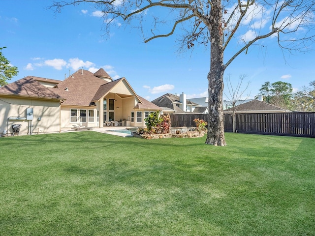 back of property with a lawn, stucco siding, a shingled roof, and a fenced backyard
