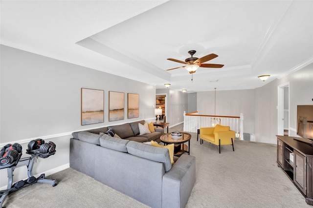 living area with a tray ceiling, ceiling fan, light colored carpet, and crown molding