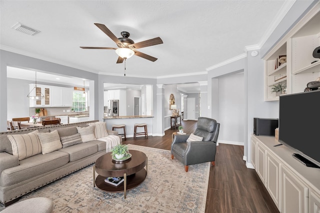 living room featuring a ceiling fan, crown molding, dark wood-style flooring, and baseboards