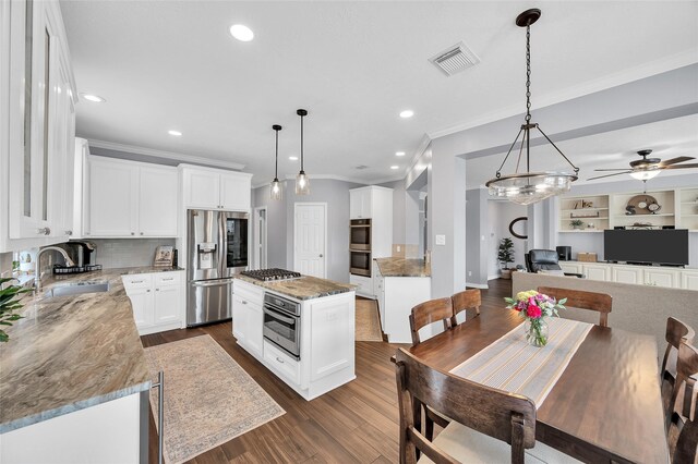 kitchen with appliances with stainless steel finishes, crown molding, a sink, decorative backsplash, and open floor plan