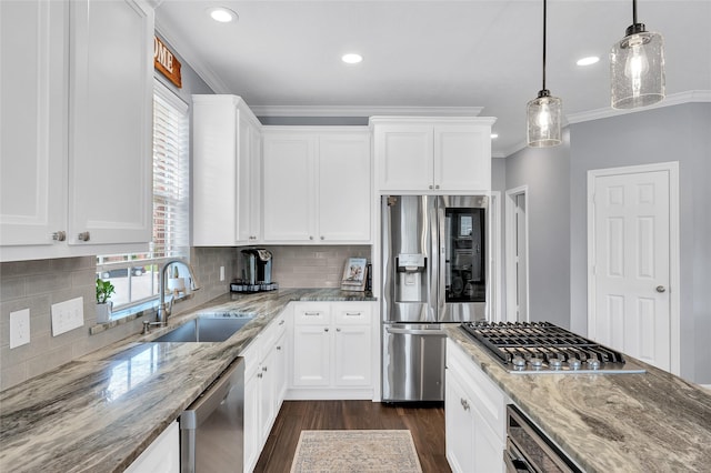kitchen with appliances with stainless steel finishes, a sink, dark wood-style flooring, light stone counters, and white cabinets
