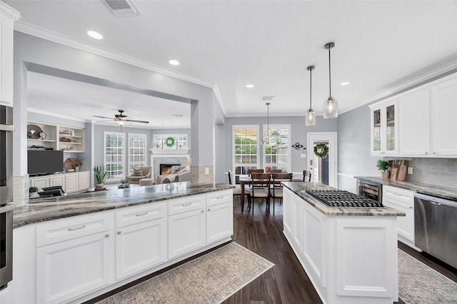 kitchen featuring ornamental molding, a lit fireplace, glass insert cabinets, dark wood-style flooring, and dark stone countertops