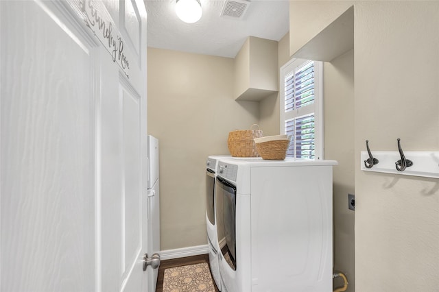 laundry area featuring washer and dryer, baseboards, and a textured ceiling