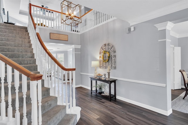 foyer featuring dark wood-style floors, stairs, baseboards, ornamental molding, and a towering ceiling