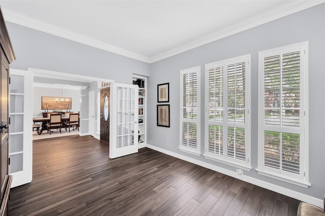 spare room with french doors, ornamental molding, plenty of natural light, a chandelier, and dark wood-style floors