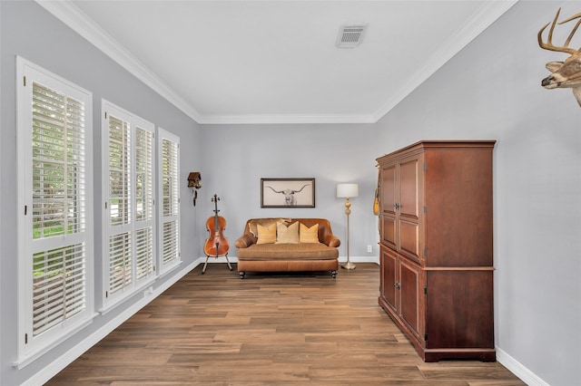 living area featuring wood finished floors, crown molding, and baseboards