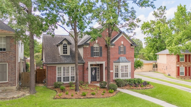 traditional-style house featuring brick siding, roof with shingles, and a detached garage