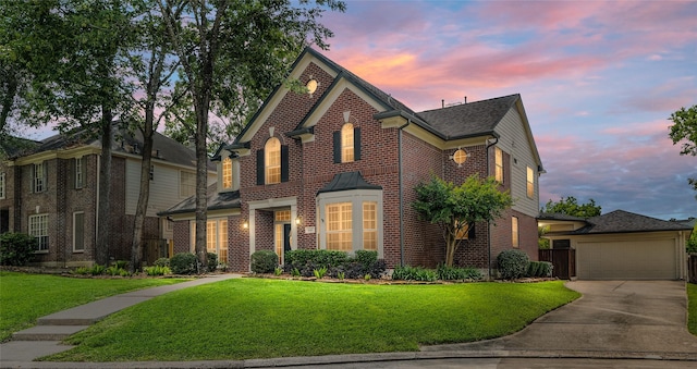 view of front facade featuring brick siding, a garage, a yard, and driveway