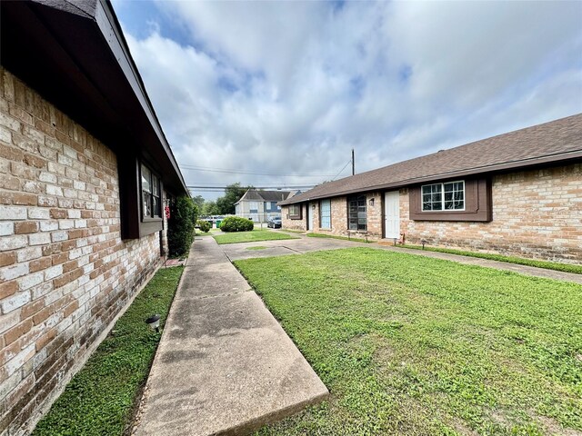 view of property exterior with brick siding, roof with shingles, and a lawn