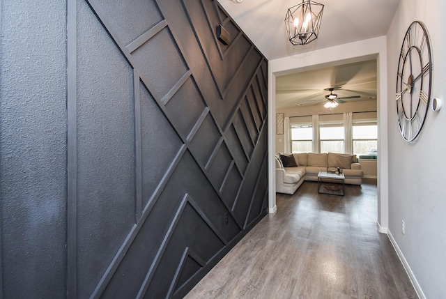 hall with baseboards, an inviting chandelier, and wood finished floors