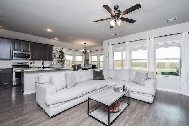 living room with visible vents, baseboards, ceiling fan with notable chandelier, and dark wood-style floors