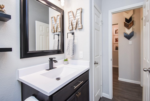 bathroom with vanity, baseboards, and wood finished floors