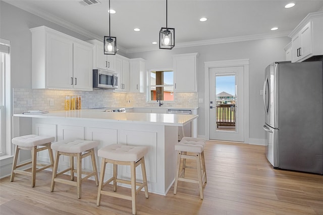 kitchen featuring stainless steel appliances, light wood finished floors, a peninsula, decorative backsplash, and light countertops